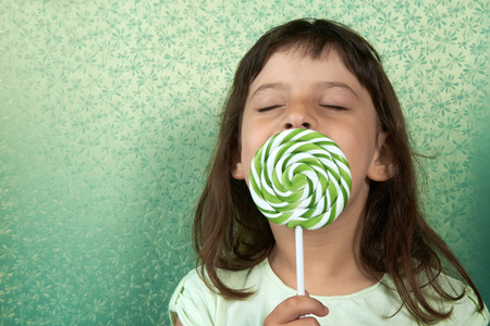 girl enjoy licking a large spiral lollipop.の写真素材
