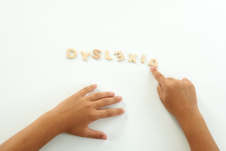 hands of a girl form the word dyslexia with wooden lettersの写真素材