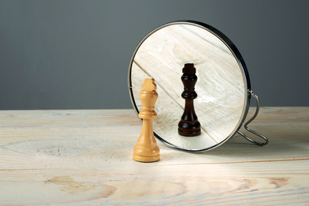 black or white king chessmen in front of the mirror, concept