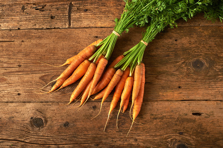 bunch of fresh carrots on a wooden tableの写真素材