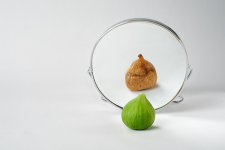 Looking older. Concept about beauty  fresh fig mirrored as a dry fig.の写真素材