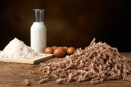 uncooked spiral pasta with manufacturing materials , flour eggs and milkの写真素材