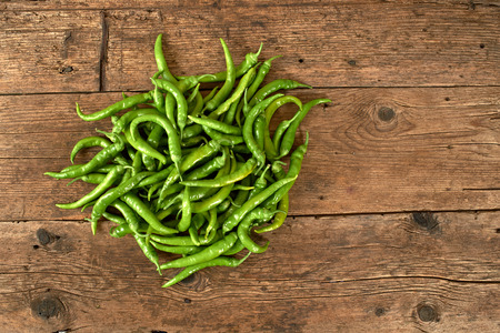 many green peppers on a wooden kitchen bench.の写真素材