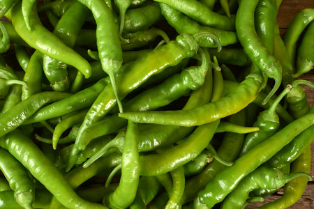 many green peppers on a wooden kitchen bench.の写真素材