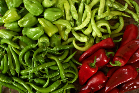 many green and red peppers on a wooden kitchen bench.の写真素材
