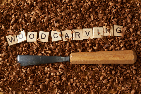 Woodworking word writen with letters on wood chips and a chiselの写真素材