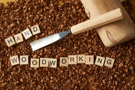 Hand woodworking word writen with letters on wood chips with chisel and a malletの写真素材