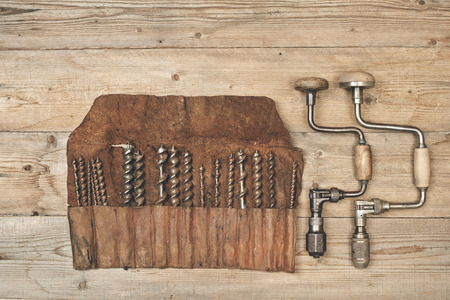 Drill braces with bits in leather tool roll on wooden workbenchの写真素材