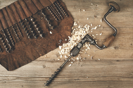 Drill brace with bits in leather tool roll on wooden workbenchの写真素材