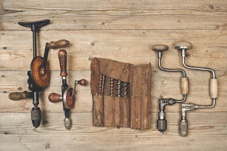 Drill braces with bits in leather tool roll on wooden workbenchの写真素材