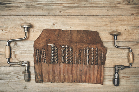 Drill braces with bits in leather tool roll on a wooden workbenchの写真素材