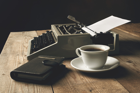 Old typewriter on a wooden table with blank paperの写真素材