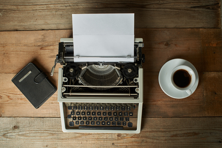 Old typewriter on a wooden table with blank paperの写真素材