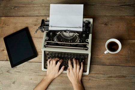 Woman is writing on an old typewriter.の写真素材