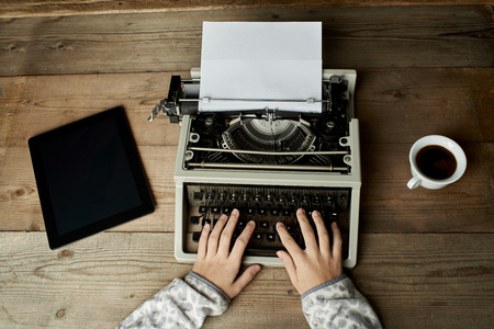 Woman is writing on an old typewriter.の写真素材