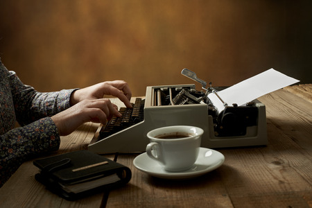 Woman is writing on an old typewriter.の写真素材