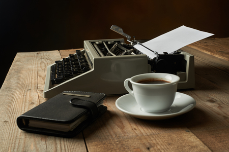 Old typewriter on a wooden table with blank paperの写真素材