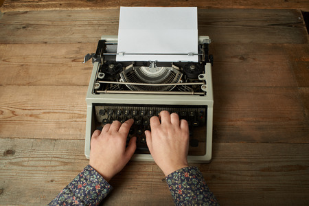 Woman is writing on an old typewriter.の写真素材