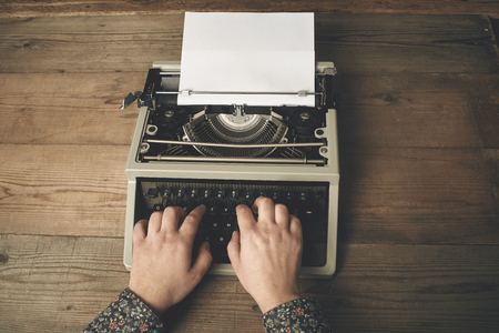 Woman is writing on an old typewriter.の写真素材
