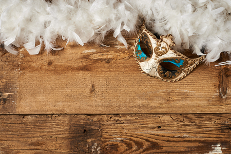 venetian carnival mask with a white feathers on wooden tableの写真素材