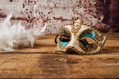 venetian carnival mask with a white feathers on wooden tableの写真素材
