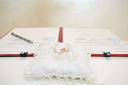 wedding rings lying on a beautiful pillow, behind them are the documents of marriage registration,...