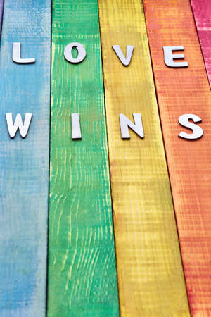 inscription love wins on wooden background in the color of lgbt community, there is free space for designer insert. suitable for articles about prideの写真素材