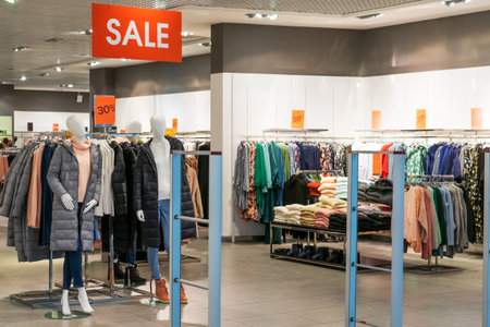 Large red sign with inscription SALE in big boutique clothing store