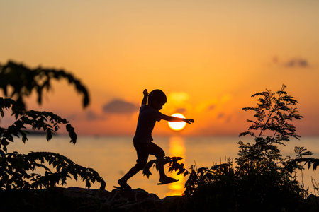 Silhouette of a jumping boy on the sunsetの写真素材