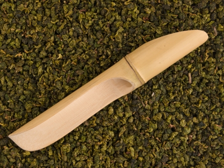 Bamboo scoop over dry green tea leaves backgroundの写真素材