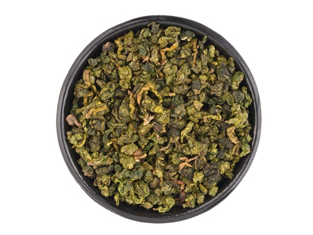 Top view of black metal bowl with dry green oolong tea leavesの写真素材