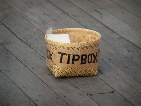 Tip box on the wooden floor waiting to be filled with money, closeup shot