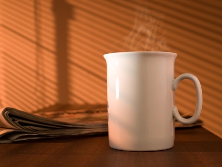 Morning coffee and newspaper on the table, lit by the sun through the windowの写真素材