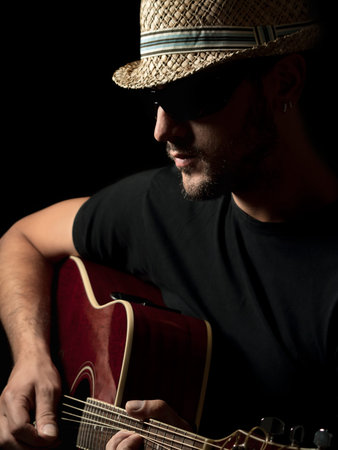 male musician wearing hat playing acoustic guitar, for concert and entertainment themes