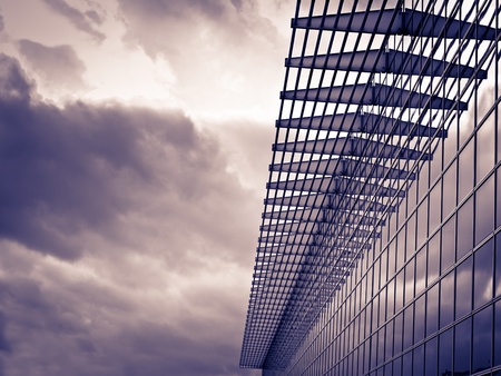 Modern glass building on the cloudy weather, toned image, for architecture,business,construction,real estate themesの写真素材