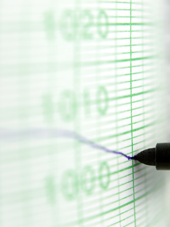 macro shot of a needle drawing the blue line ,showing downword trend on the graph paper ,shallow DOFの写真素材