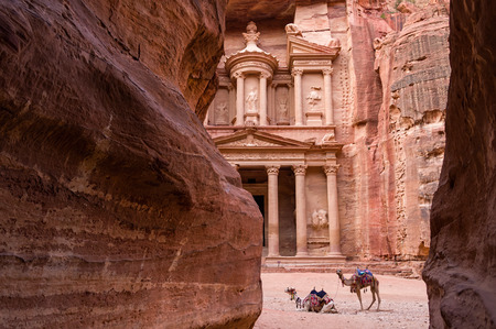 Ancient nabataean temple Al Khazneh (Treasury) located at Rose city - Petra, Jordan. Two camels infront of entrance. View from Siq canyon.の写真素材