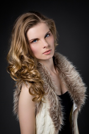 Beautiful blonde woman in fur, dark backgroundの写真素材
