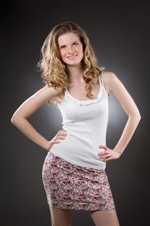 Smiling blonde woman standing in white top, flower skirtの写真素材