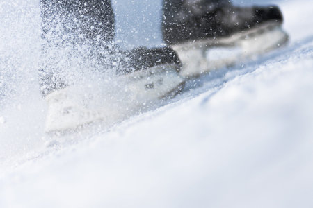 Snow flying from braking, ice skates blurred