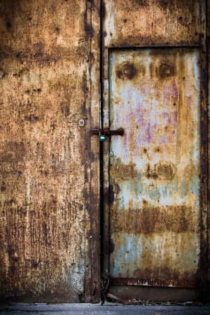 Rusty old brown metal door with a lockの写真素材
