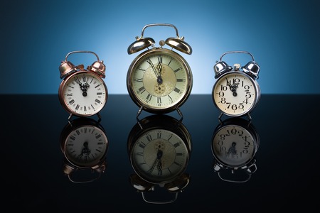 Vintage alarm clocks showing five minutes to twelve, blue backgroundの写真素材