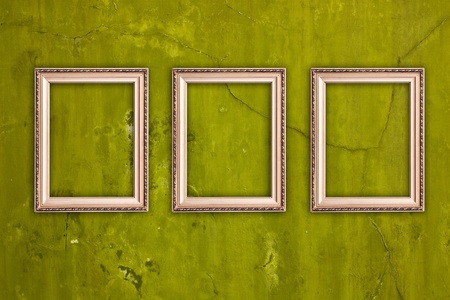 three blank frames hanging on vintage green cracked wallの写真素材