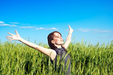 young woman with hands raised up in the wheat fieldの写真素材