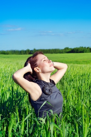 young woman with hands raised up in the wheat field の写真素材