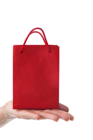 female hand holding red gift bag with present with her fingers - shopping and holiday concept の写真素材