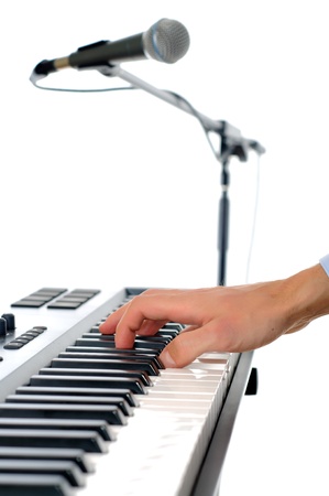 maicrophone and male hands playing the piano in the studio isolated on white - shallow pepth of firld with focus plased on handの写真素材