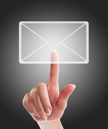 female hand pressing e-mail  sign on a touch screen interface over black and grey backgroundの写真素材