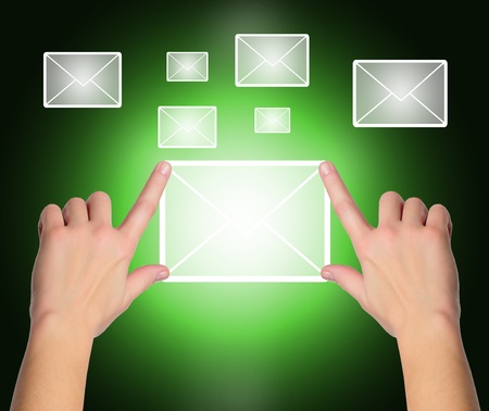 female hand pressing e-mail sign on a touch screen interface over black and blue background の写真素材