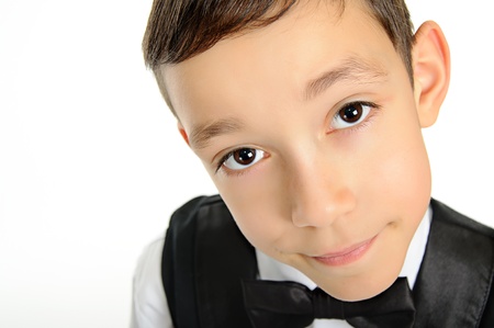 portrait of a young school boy in black suit with deep brown eyes looking at camera isolated on white background の写真素材